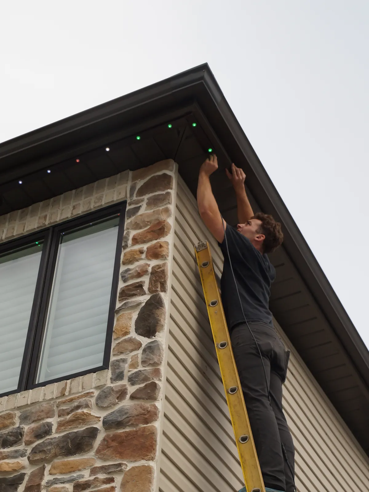 An installer at the top of a ladder at the roof edge