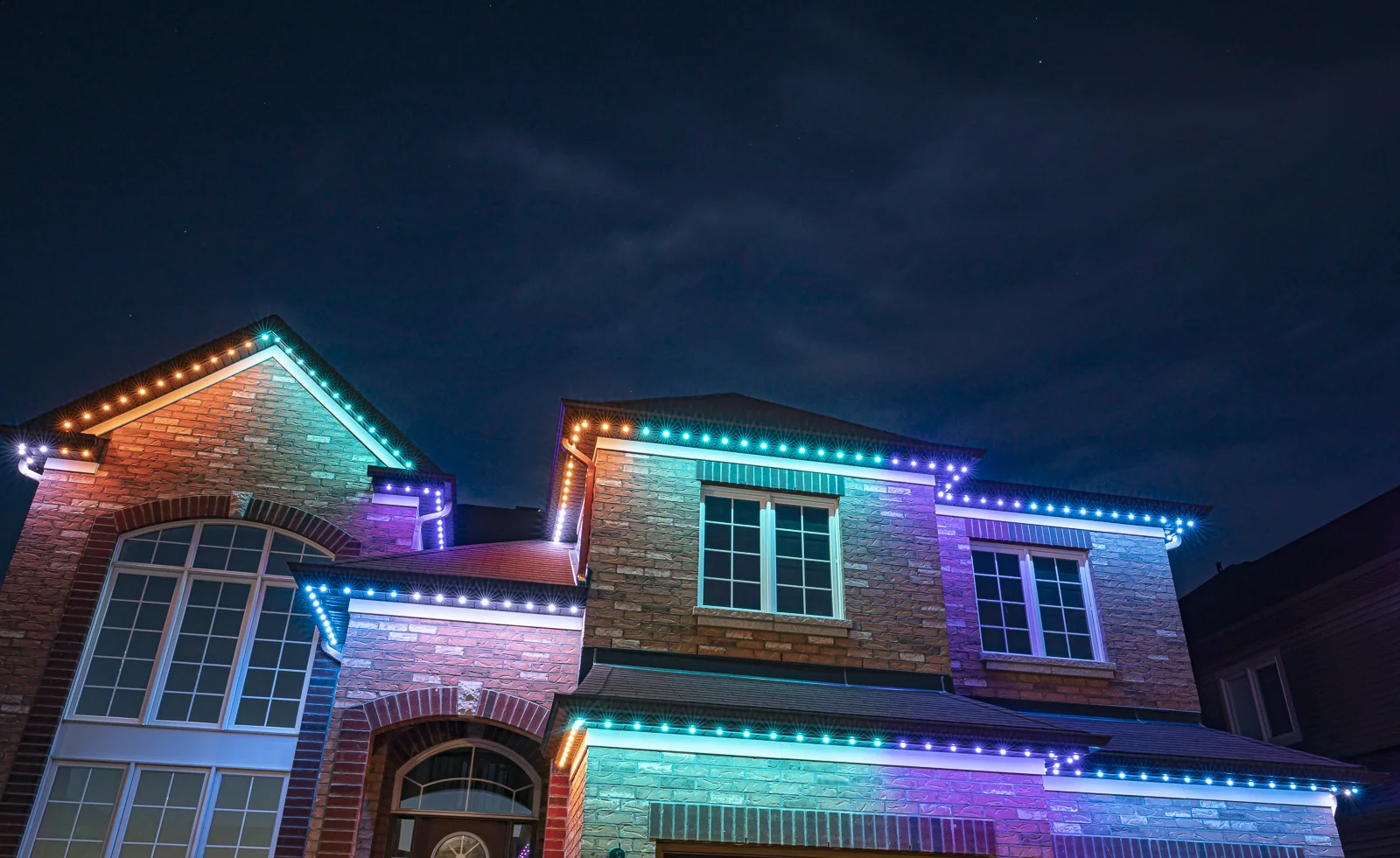 A brick home with rooflines in teal, purple and orange