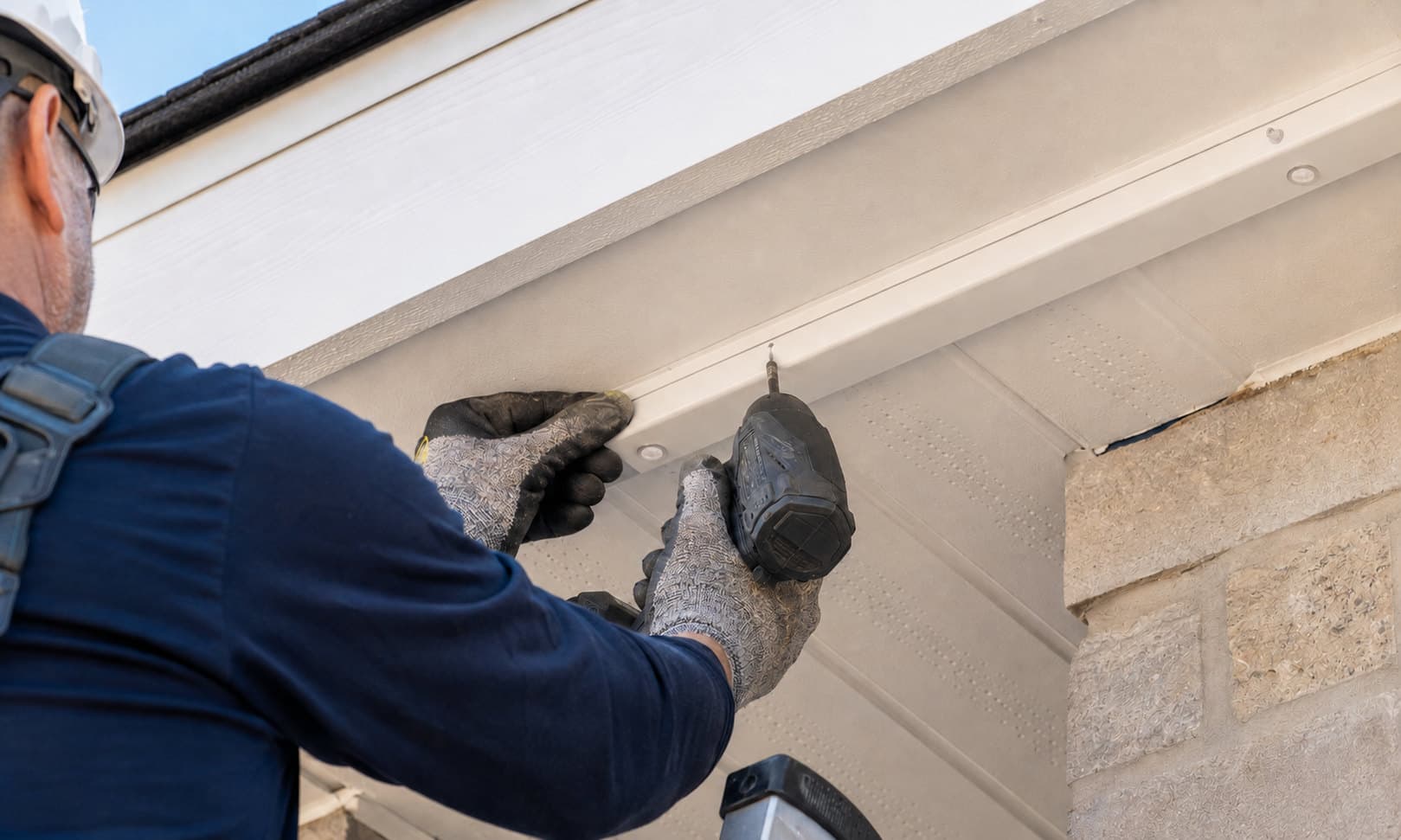Illustration of an installer in gloves and a hard hat fastening a concealed lighting channel along a soffit